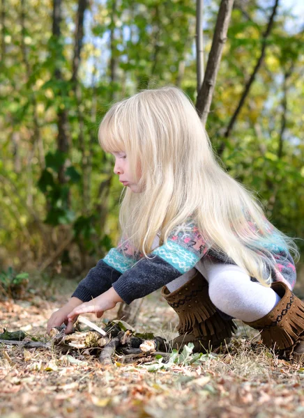 Niña rubia jugando con palos secos — Foto de Stock