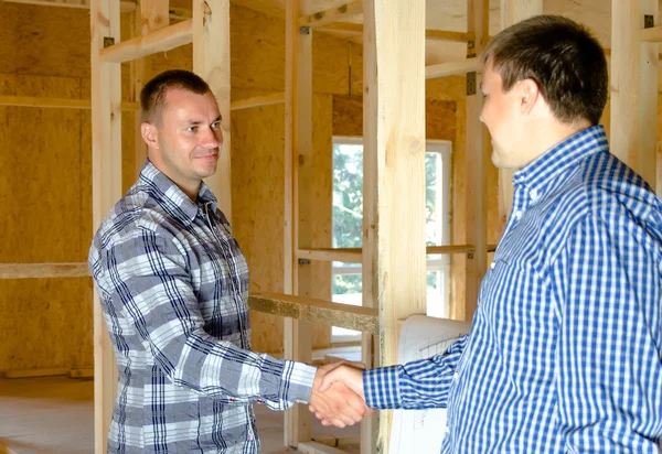 Dois homens apertando as mãos em uma nova casa de construção — Fotografia de Stock