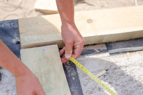 Hands of a carpenter taking a diagonal measurement — Stock Photo, Image