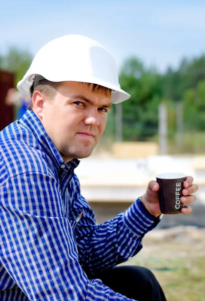 Workman drinking coffee in his hardhat — Stock Photo, Image