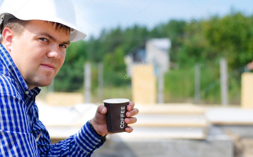 Workman drinking coffee in his hardhat