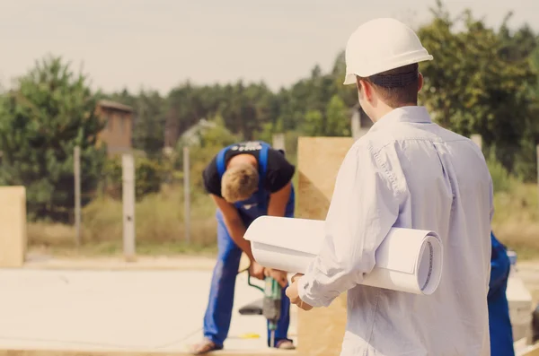 Architetto in piedi a guardare i costruttori al lavoro — Foto Stock