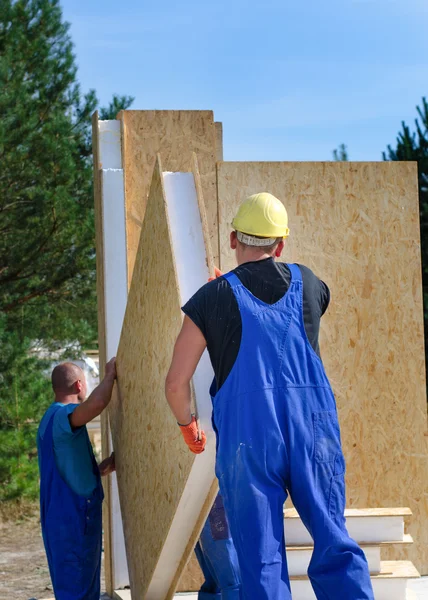 Dois construtores instalando um painel de parede de madeira — Fotografia de Stock