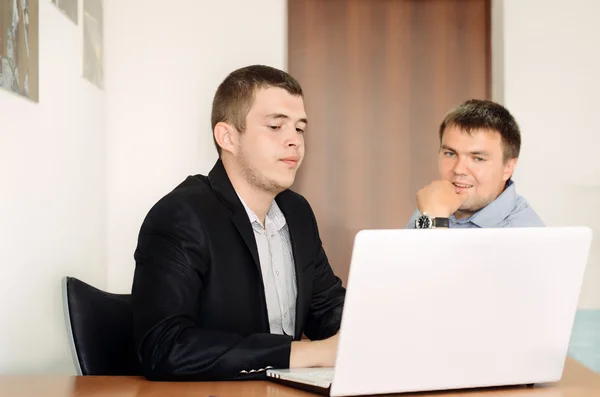 Jóvenes hombres de negocios mirando el ordenador portátil en la mesa — Foto de Stock
