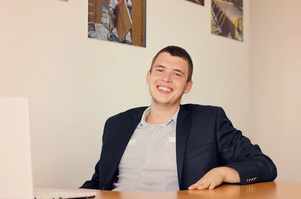 Empresário sorridente com laptop no escritório — Fotografia de Stock