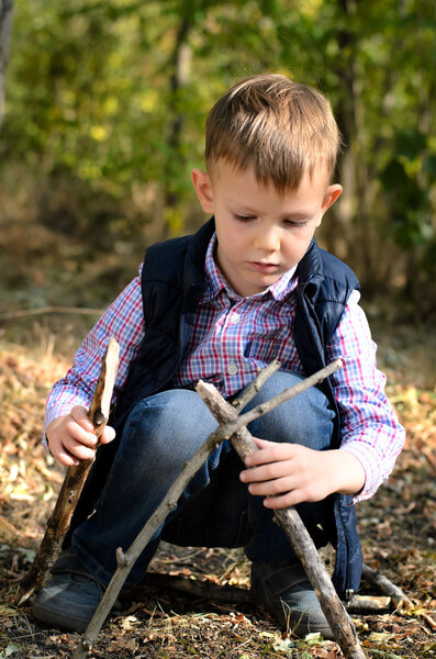 Cute Little Boy Playing with Sticks at the Woods