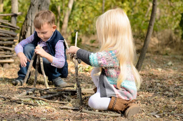 Menino e menina brincando na floresta com paus — Fotografia de Stock