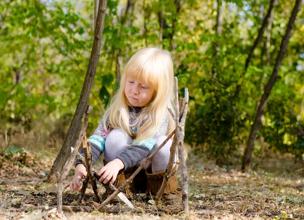 Allvarliga Blond flicka montering pinnar på marken — Stockfoto