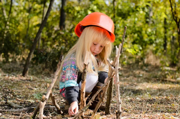 Menina com capacete brincando com paus — Fotografia de Stock