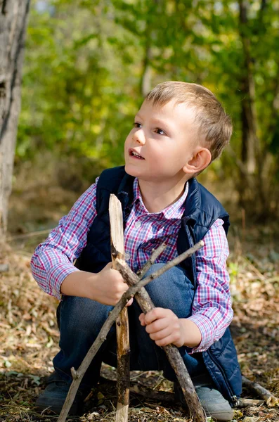 Menino bonito brincando com paus na floresta — Fotografia de Stock