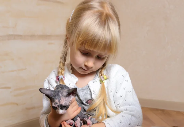 Blond meisje houdt van een kitten sphynx — Stockfoto