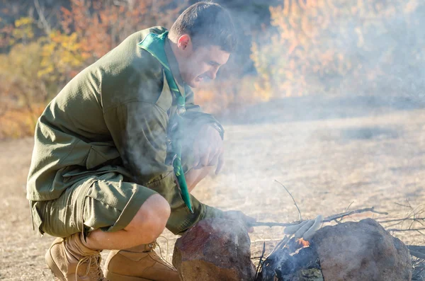 Boy Scout koken worst op stokjes boven kampvuur — Stockfoto