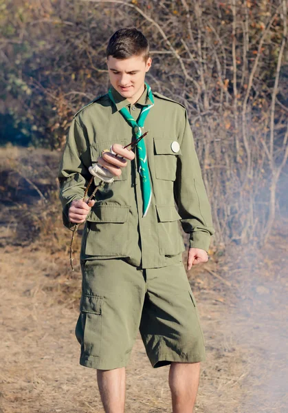 Boy Scout with Stick of Sausages by Campfire