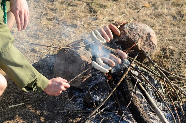 Cocinar salchichas en palos sobre fogata —  Fotos de Stock