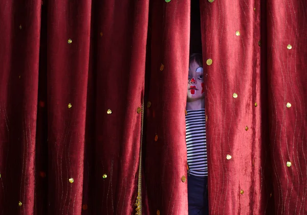 Pojke Clown tittar fram genom scenen gardiner — Stockfoto