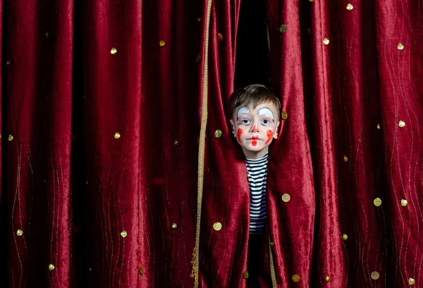 Хлопчик клоун дивиться крізь сценічні штори — стокове фото