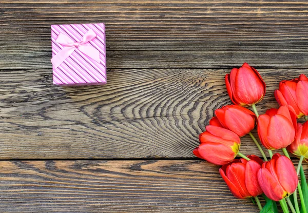 Buquê de tulipas frescas com um presente — Fotografia de Stock