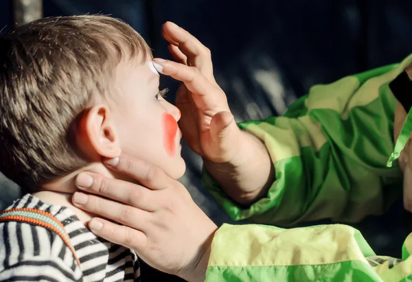 Uomo che applica la pittura facciale a un bambino — Foto Stock