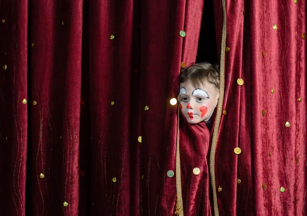 Chico payaso mirando a través de cortinas de escenario — Foto de Stock