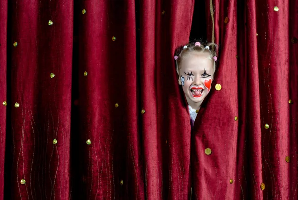Flicka klädd i Clown Makeup tittade genom gardiner — Stockfoto