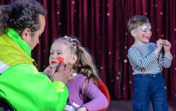 Junges Mädchen von einem Künstler mit Clown-Make-up geschminkt — Stockfoto