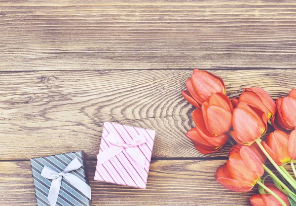 Tulipanes en mesa de madera con pequeñas cajas de regalo —  Fotos de Stock