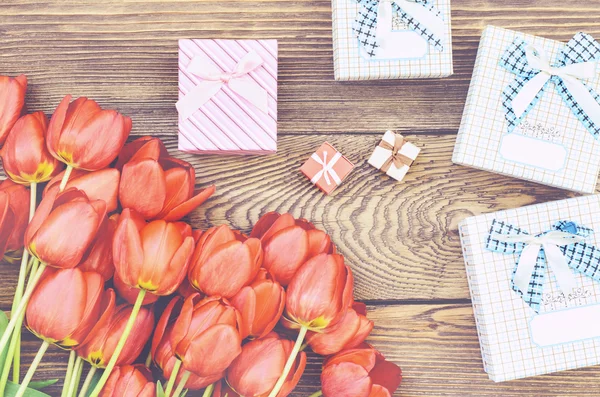 Kytice tulipánů na dřevěný stůl s dárky Royalty Free Stock Fotografie