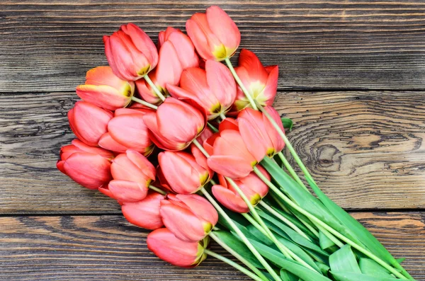 Tulipanes rojos frescos sobre un fondo texturizado de madera —  Fotos de Stock