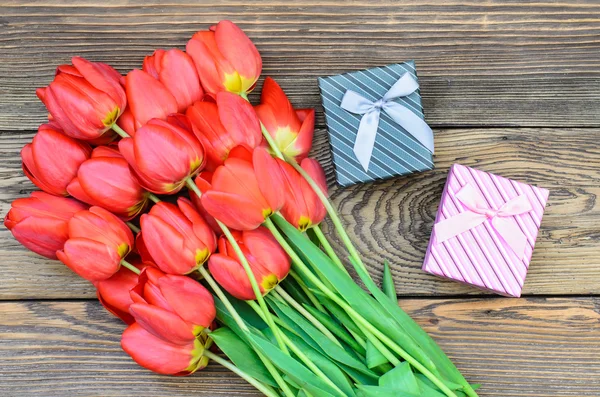 Tulipanes en mesa de madera con pequeñas cajas de regalo — Foto de Stock