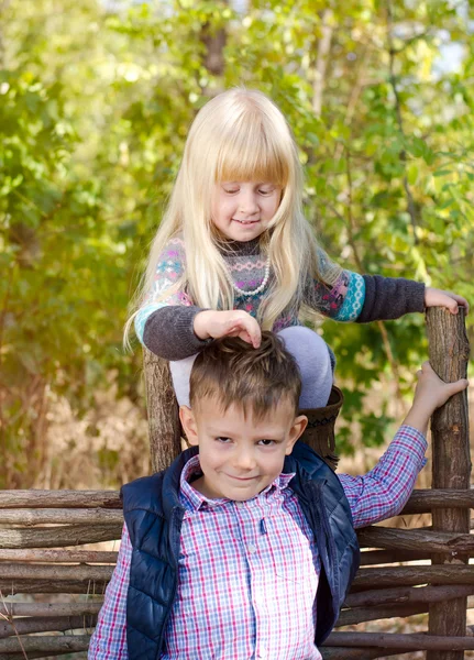 Nettes blondes Mädchen spielt die Haare ihres Bruders — Stockfoto