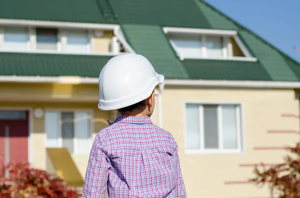 Niño usando casco duro de pie frente a la casa — Foto de Stock