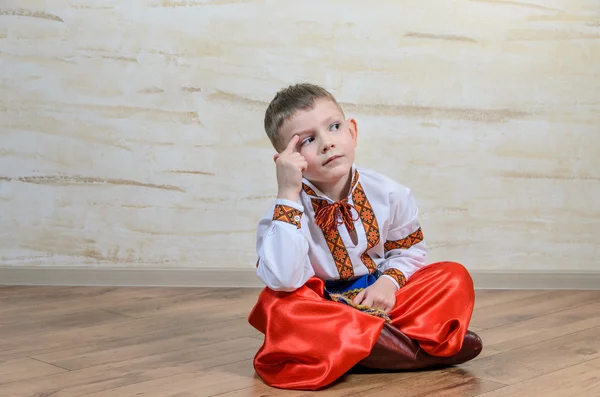 Cute young boy sitting thinking — Stock Photo, Image