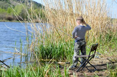 bir göl kıyısında balık tutan genç çocuk