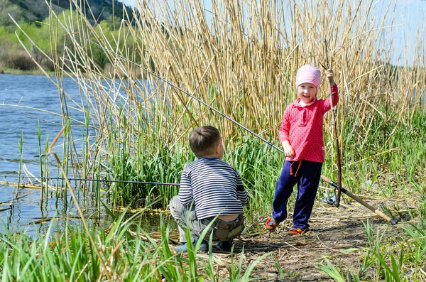 Dos hermanos sosteniendo cañas de pescar en la orilla del río —  Fotos de Stock