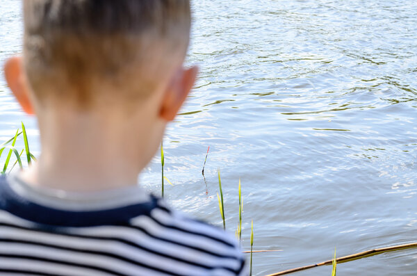 Young Male Kid Fishing at the River Alone