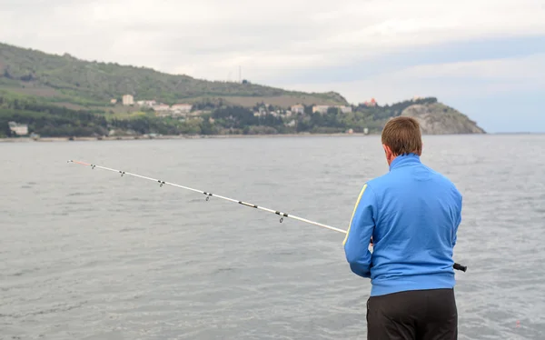 Man staande visserij aan de kust — Stockfoto