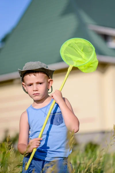 Pojken i fältet anläggning gröna bugg netto — Stockfoto