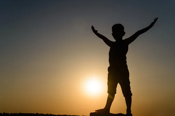 Silhouette del giovane ragazzo in piedi a braccia aperte — Foto Stock