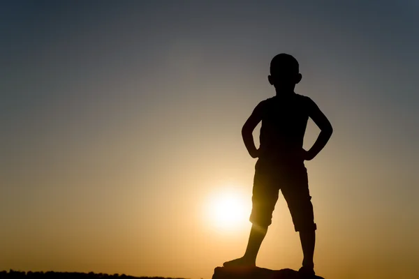 Silhouette di ragazzo in piedi con le mani sui fianchi — Foto Stock