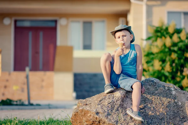 Jongen zittend op boulder ijsje eten — Stockfoto