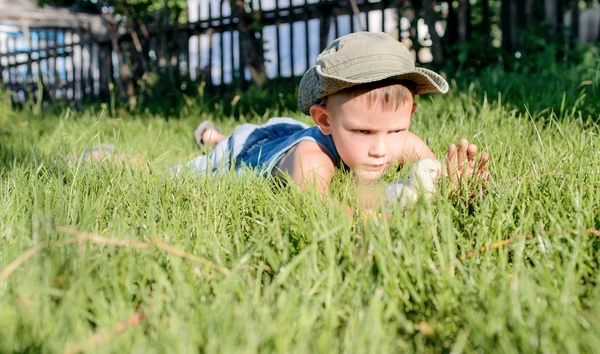 Młody chłopiec bawi się laska w długiej trawy — Zdjęcie stockowe