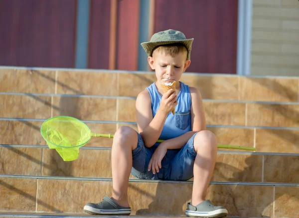 Pojke med bugg net äta glass på stegen i hem — Stockfoto