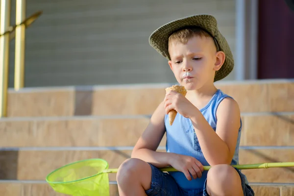 Chłopiec z błędów netto siedzi na kroki jeść lody — Zdjęcie stockowe
