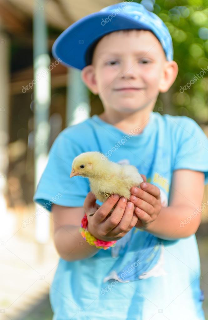 Smiling little boy holding a young chick