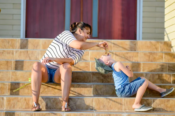 Madre alimentando helado al hijo en pasos del hogar —  Fotos de Stock