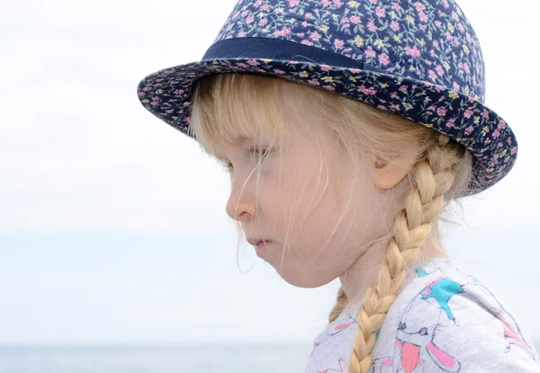 Blond meisje met bloemen hoed op zoek naar afstand — Stockfoto