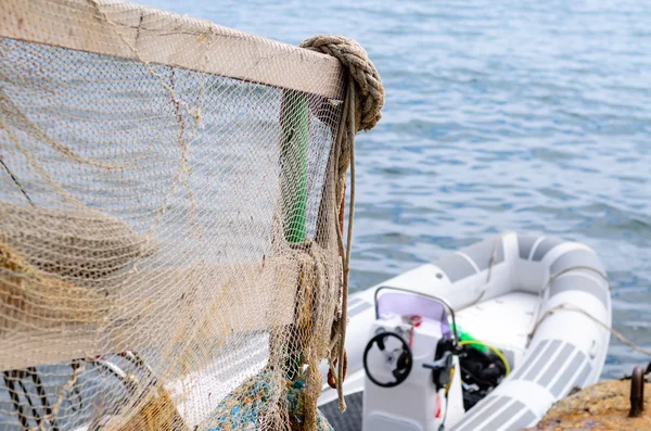 Geländer drapiert in Fischernetz auf Dock mit Boot — Stockfoto