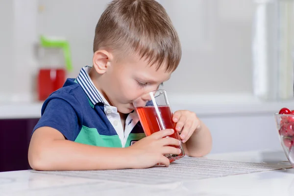 Liten pojke dricka fruktjuice i ett kök — Stockfoto