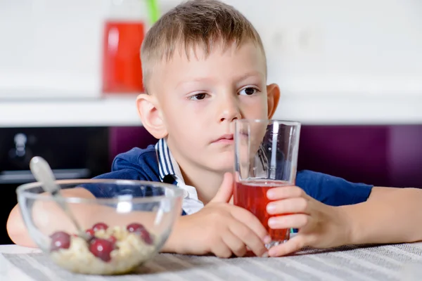 Little boy drinking fruit juice in a kitchen — Stock Photo, Image