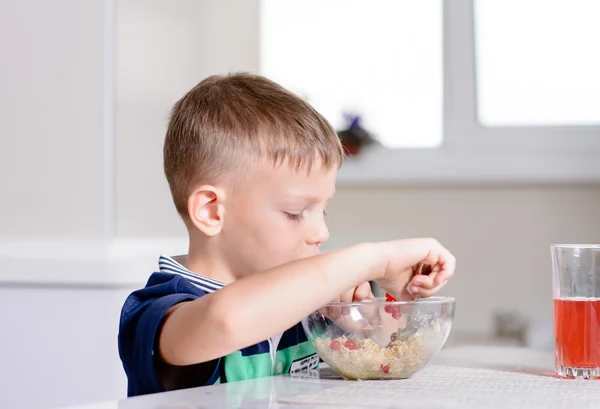 Jonge jongen aan ontbijttafel eten kom van granen — Stockfoto